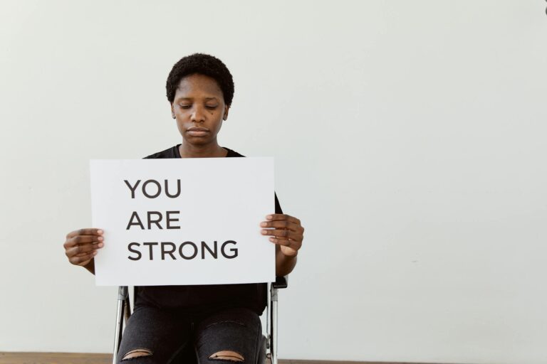 Woman holding 'You Are Strong' sign, promoting empowerment and motivation.